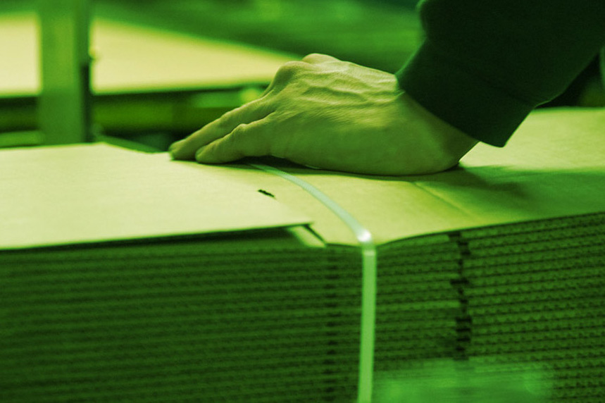 Hand resting on a stack of green cardboard sheets